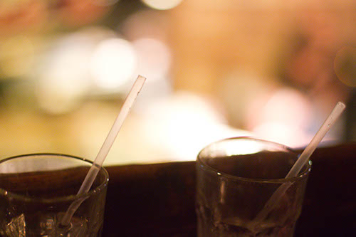 Two empty drinks sit on bar rail overlooking dance floor below