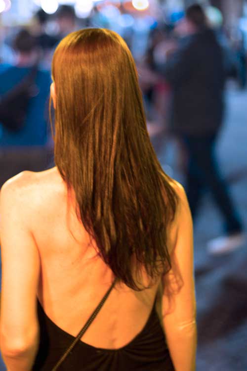 A woman in backless dress walks along sixth street